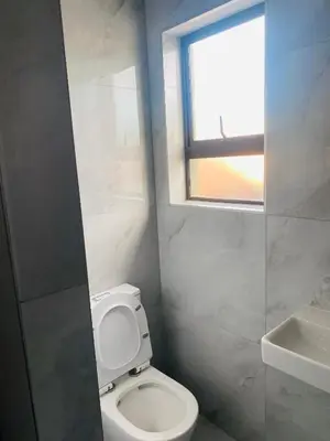 a bathroom with a white toilet and a window at Plattekloof Queens Guest House in Welgelegen