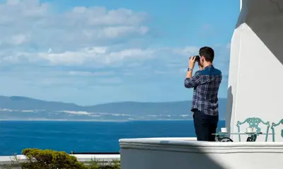 a man talking on a cell phone while looking at the ocean at The Marine Hermanus in Hermanus