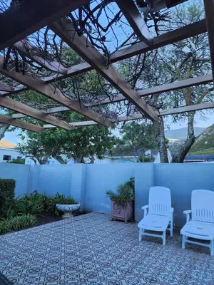 a patio with two white chairs and a fence at 51 on 6th in Hermanus