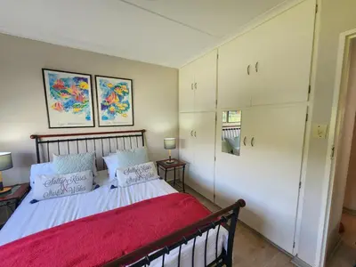 a bedroom with a bed with a red blanket at 51 on 6th in Hermanus