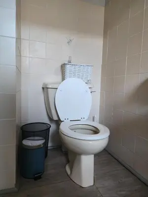 a bathroom with a white toilet and a trash can at 51 on 6th in Hermanus