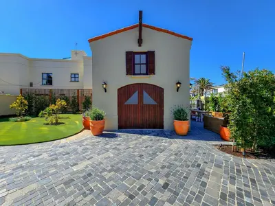 a house with a garage and a brick driveway at Luxury beachfront villa Cape Town - Sunset Beach in Cape Town