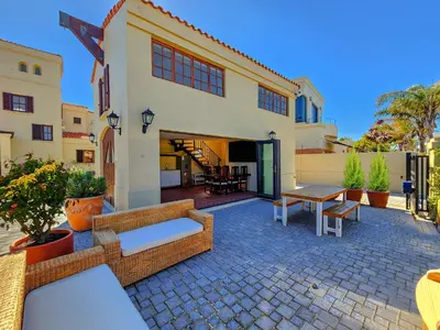 a house with a patio with tables and benches at Luxury beachfront villa Cape Town - Sunset Beach in Cape Town
