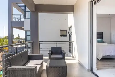 a balcony with a bed and two chairs and a bedroom at Greystone Serenity 2-Bedroom Apartment in Cape Town