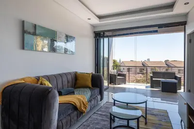 a living room with a couch and a table at Greystone Serenity 2-Bedroom Apartment in Cape Town