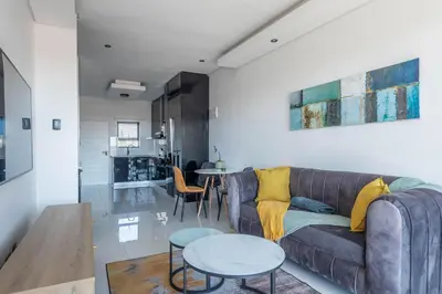 a living room with a couch and a table at Greystone Serenity 2-Bedroom Apartment in Cape Town