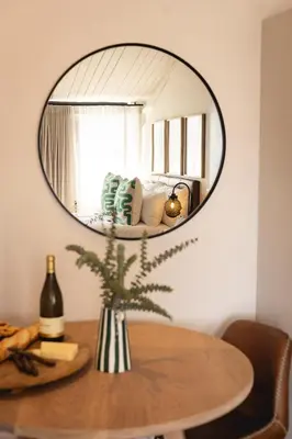 a round mirror hanging on a wall above a table at Waterfront Studios - Hermanus Waterfront Apartments in Hermanus
