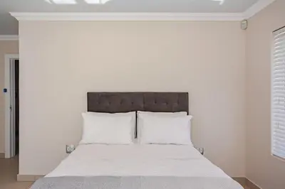 a white bedroom with a large bed with white pillows at Cassamo house in Cape Town