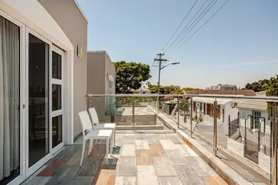 a balcony with white chairs on a house at Cassamo house in Cape Town