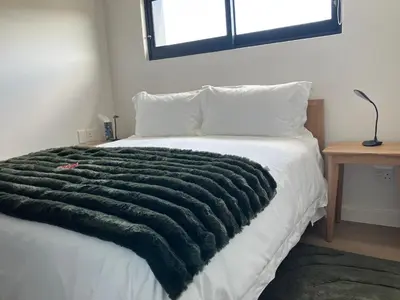 a green blanket laying on top of a bed at The Wild Oak in Hermanus