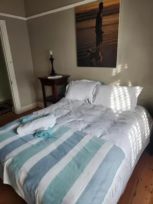 a large bed with a striped blanket on it at Strand Beach House in Strand
