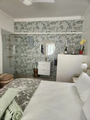 a bedroom with a large bed and a mirror at Strand Beach House in Strand
