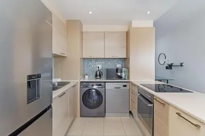 a kitchen with a washing machine and a dishwasher at Stylish 2-Bedroom Sea-View Apartment Horizon Bay Blouberg Beachfront in Cape Town