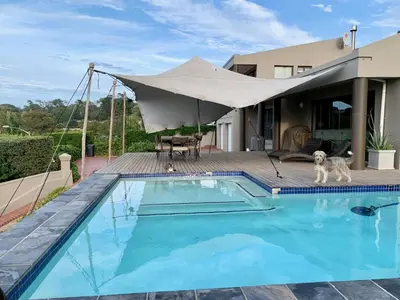 a dog is standing next to a swimming pool at Dream Views in Somerset West