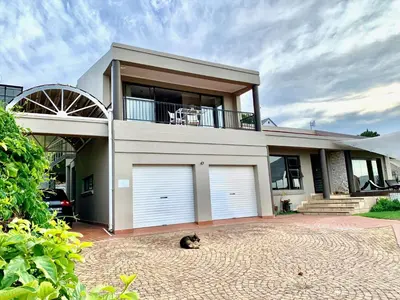 a cat sitting in front of a house with two garage doors at Dream Views in Somerset West