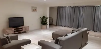 a living room with couches and a flat screen tv at Cottage on Abelia in Helderberg