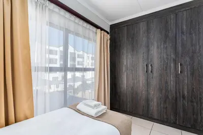 a bedroom with wooden cabinets and a large window at The Sandown 178 by CTHA in Cape Town