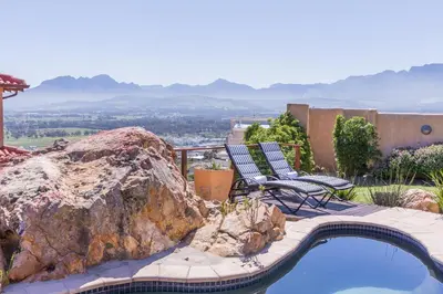 a pool with two chairs and a large rock at Blue Horizon Guest House in Gordonʼs Bay