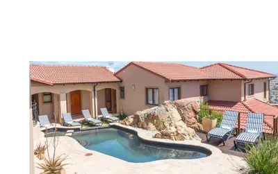 a house with a swimming pool and two lawn chairs at Blue Horizon Guest House in Gordonʼs Bay