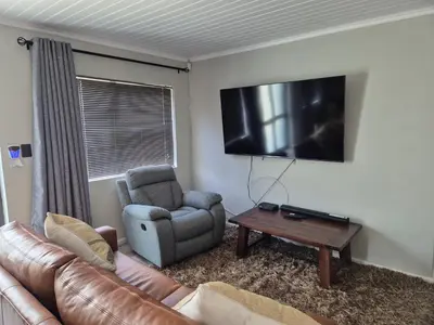 a living room with a couch and a chair and a television at Remmy Place in Hawston