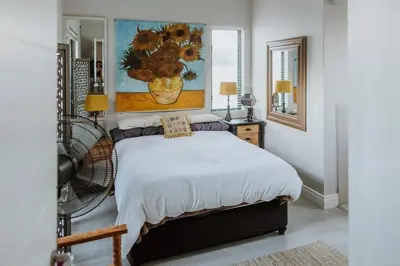 a bedroom with a bed with a painting on the wall at Between the Ocean and Winelands in Croydon
