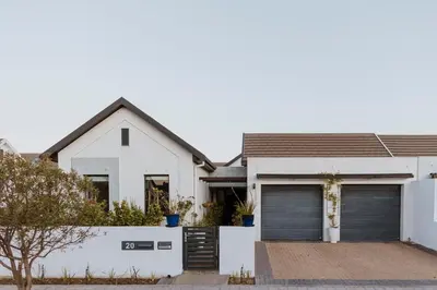 a white house with two garage doors at Between the Ocean and Winelands in Croydon