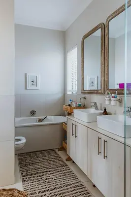 a bathroom with two sinks and two mirrors at Between the Ocean and Winelands in Croydon
