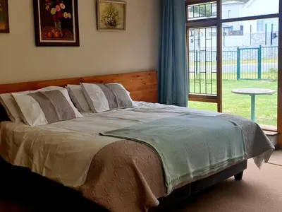 a bed in a bedroom with a large window at Happidaze in Hermanus
