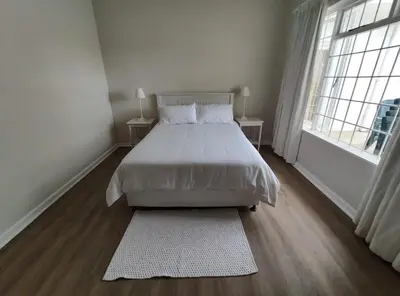a bedroom with a white bed and a window at Voëlklip House - Home with Pool & Mountain views in Hermanus