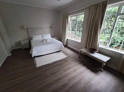 a bedroom with a white bed and two windows at Voëlklip House - Home with Pool & Mountain views in Hermanus