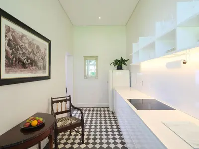 a white kitchen with a table and a refrigerator at Adara Palmiet Valley Luxurious Boutique Farm Hotel in Paarl