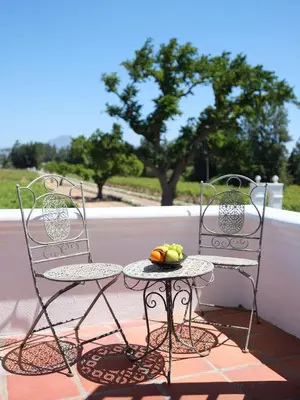 two chairs and a table with a bowl of fruit on a porch at Adara Palmiet Valley Luxurious Boutique Farm Hotel in Paarl