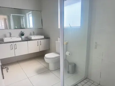 a bathroom with a toilet and two sinks and a shower at Villa Sunn in Cape Town