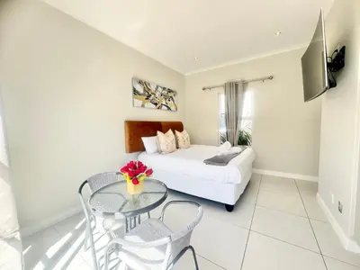 a living room with a bed and a glass table at Villa Sunn in Cape Town