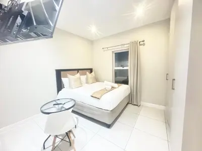 a small white bedroom with a bed and a table at Villa Sunn in Cape Town