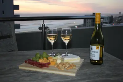 a bottle of wine and two glasses on a table at Luxurious 3-bedroom Bloubergstrand Cape Town beachfront apartment with stunning sea and beach view in Cape Town
