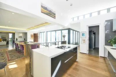 a kitchen with a white counter top and a living room at On Golf Estate Sea & Mountain Views Design Winner in Hermanus
