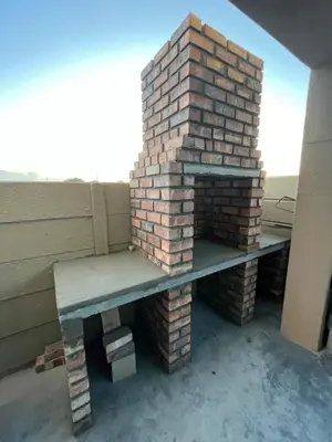 a brick fireplace with a bench on a patio at SNE Travellers in Faure