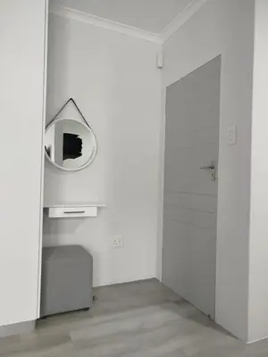 a white room with a mirror and a door at Hermanus C-Escape Apartment in Hermanus