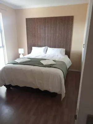 a bedroom with a large bed with white sheets and pillows at Blouberg Holiday Haven in Cape Town