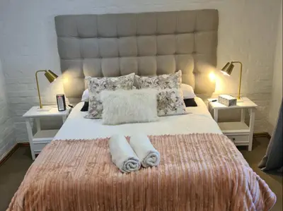 a bedroom with a large bed with two towels on it at Franschhoek Farm Cottages in Franschhoek
