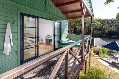 a green house with a wooden porch and a deck at Elgin River Lodge in Elgin