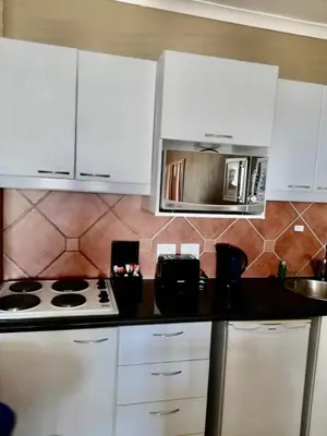a kitchen with white cabinets and a stove and a microwave at Cape Town Beachfront Apartments at Leisure Bay in Cape Town