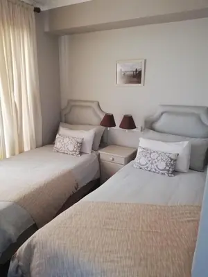 a bedroom with two beds and a window at Cape Town Beachfront Apartments at Leisure Bay in Cape Town