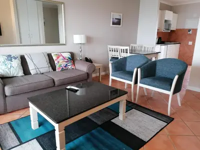 a living room with a couch and two chairs and a table at Cape Town Beachfront Apartments at Leisure Bay in Cape Town