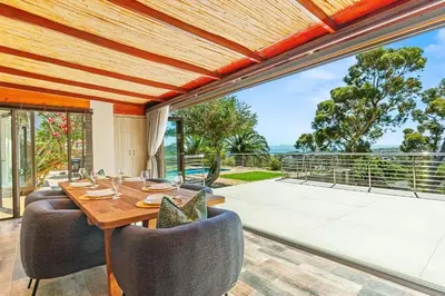a dining room with a table and chairs and a balcony at 97 Drommedaris by Host Agents in Cape Town