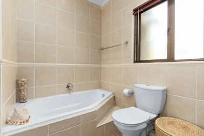 a bathroom with a tub and a toilet and a sink at 97 Drommedaris by Host Agents in Cape Town