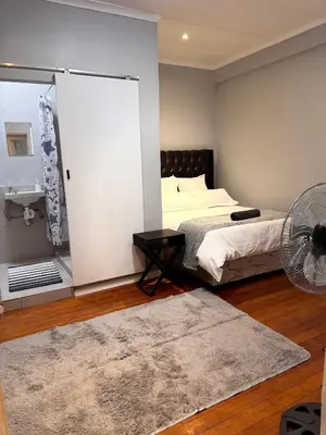 a bedroom with a bed and a fan at HavenTrust Guest house in Goodwood