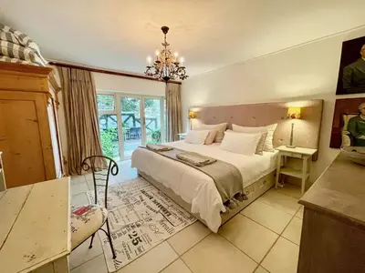 a bedroom with a large bed and a chandelier at Garden Hideaway in Stellenbosch