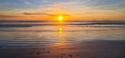 a sunset on a beach with the sun setting at Sunbird room in Cape Town